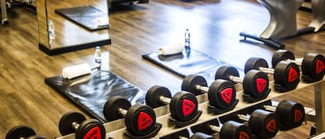 A gym with a mirror, exercise equipment, and a treadmill.