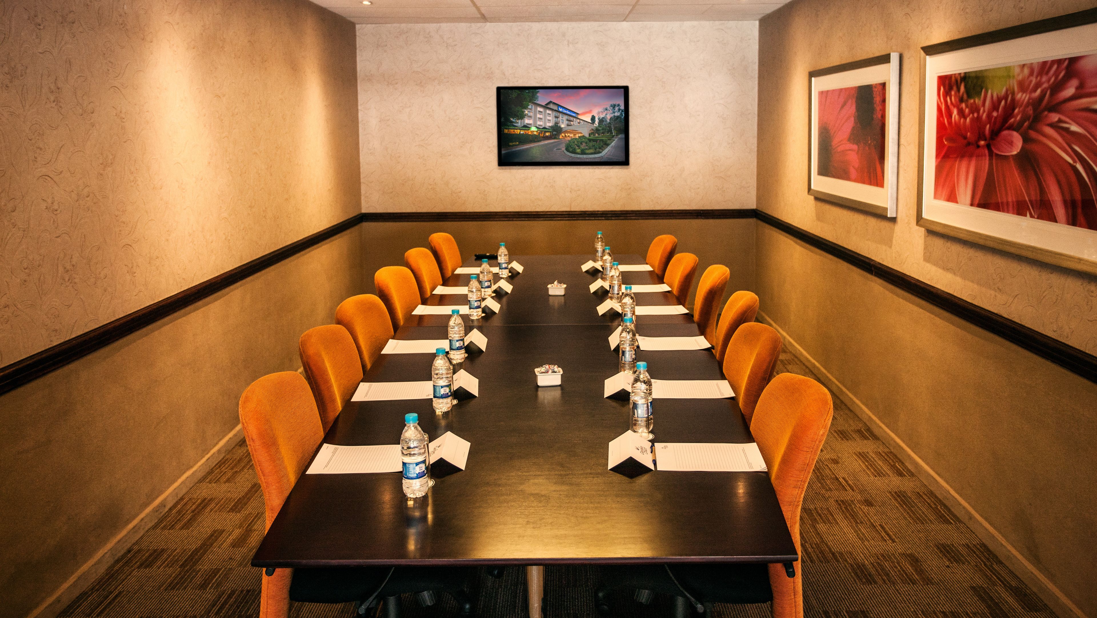 A conference room with a long table, orange chairs, water bottles, and papers.