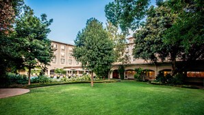 A courtyard with a lawn, trees, and a building with multiple windows and balconies. - Garden Court O.R. Tambo International Airport (Kempton Park)