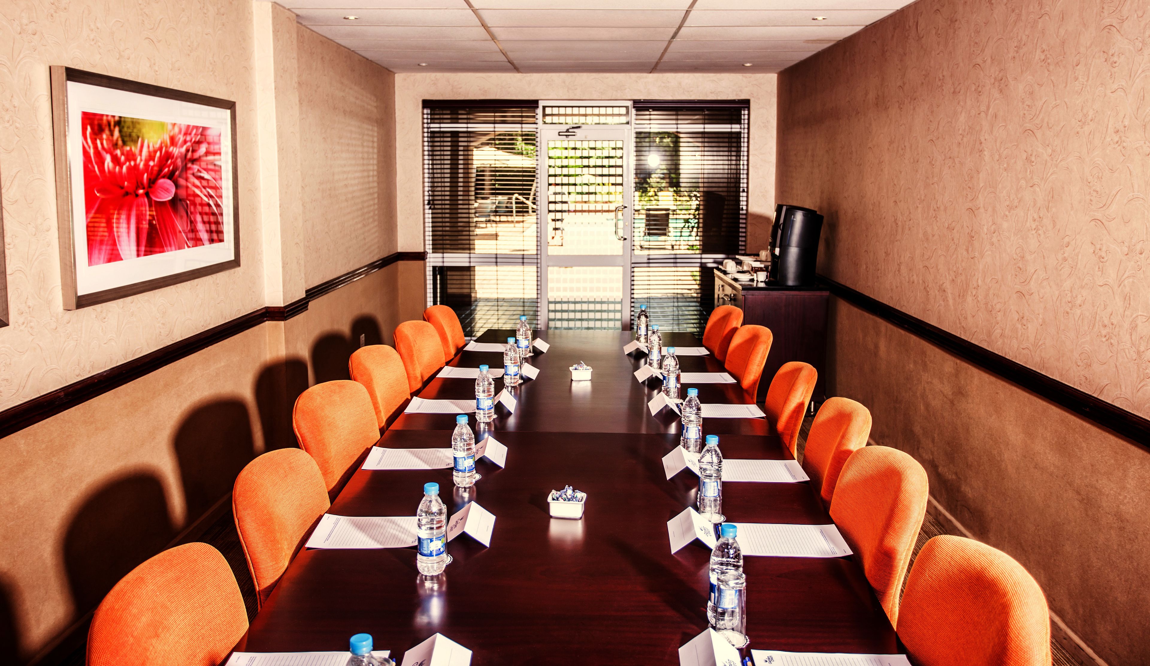 A conference room with a long table, orange chairs, water bottles, and name cards.