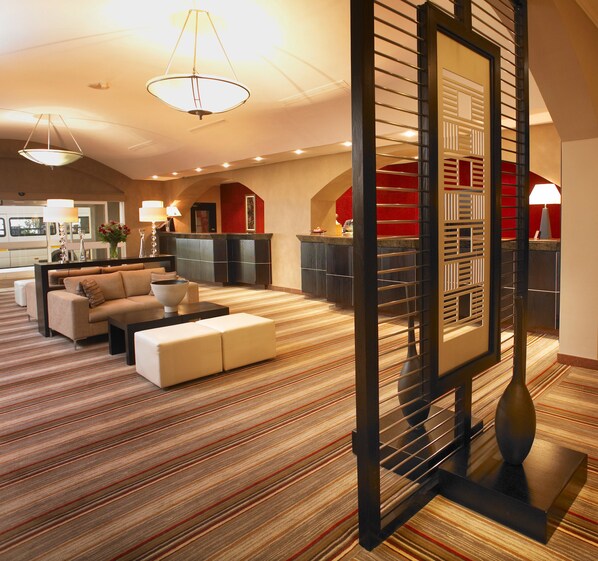 A spacious living area with a sofa set, a coffee table, and a striped carpet.