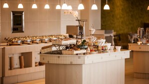Een buffetopstelling met meerdere aaneenschakelde stations, een centraal eiland met een bloevas en hangende hanglampen.
