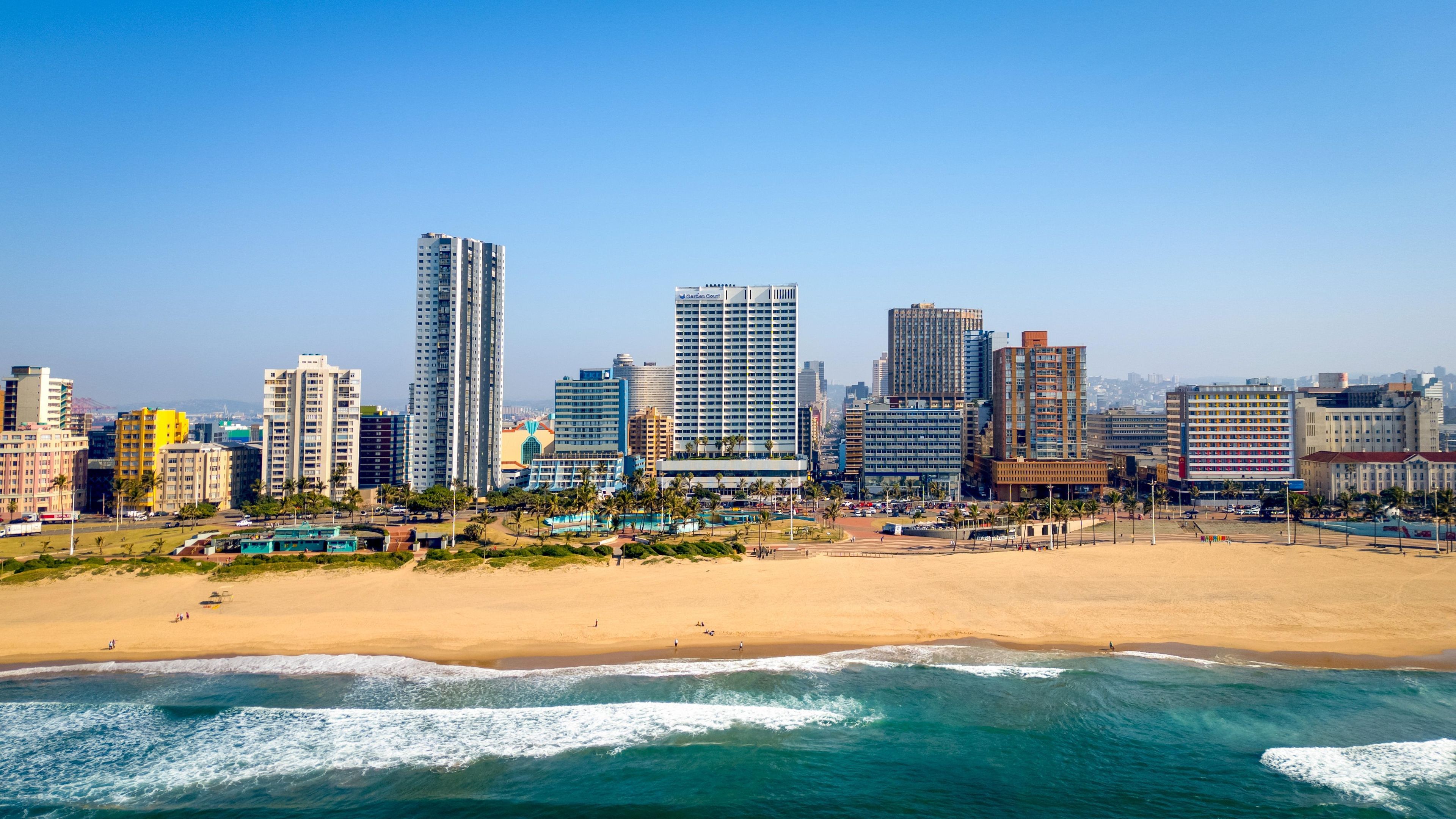 A coastal cityscape with high-rise buildings, a sandy beach, and the ocean.
