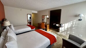 Une chambre d’hôtel avec deux lits, un bureau, une chaise, un miroir et un téléviseur.