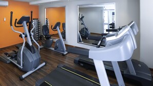 Une salle de sport équipée de tapis de course, de vélos elliptiques et de poids.