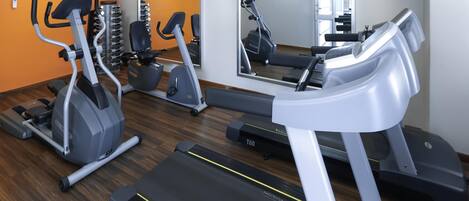 A gym with treadmills, elliptical machines, and a weight rack.