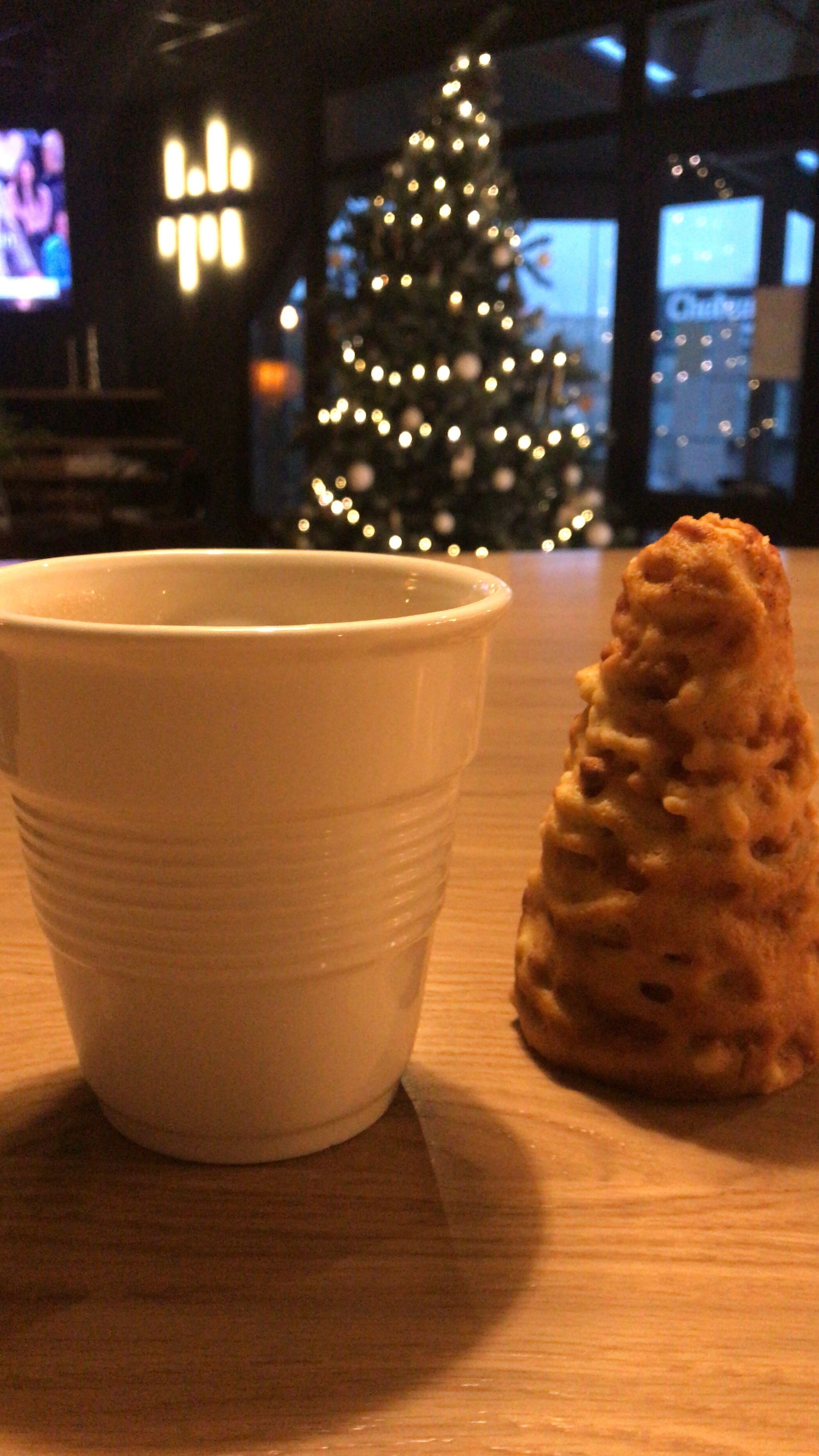 Una taza de cerámica blanca y un alimento con textura sobre una mesa de madera.