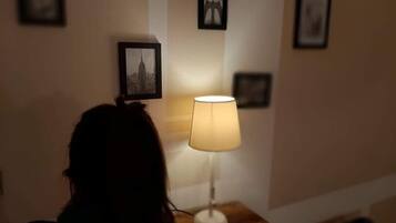 Una habitación con un mesita de noche de madera, una lámpara y cuadros en la pared.