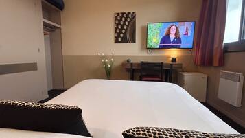 Een hotelkamer met een bed, bureau, televisie en radiator.