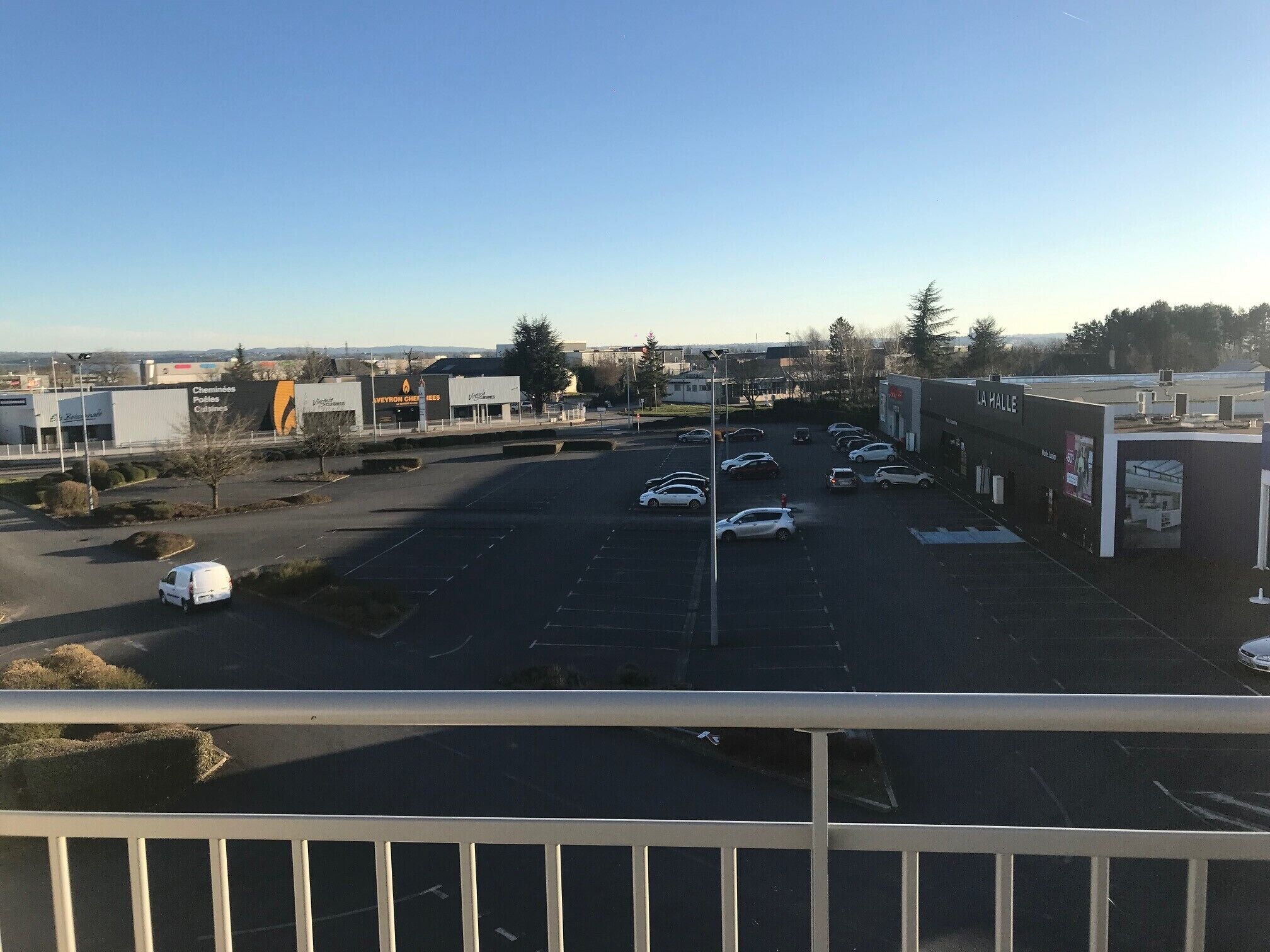 A parking lot with several cars and a few buildings in the background.