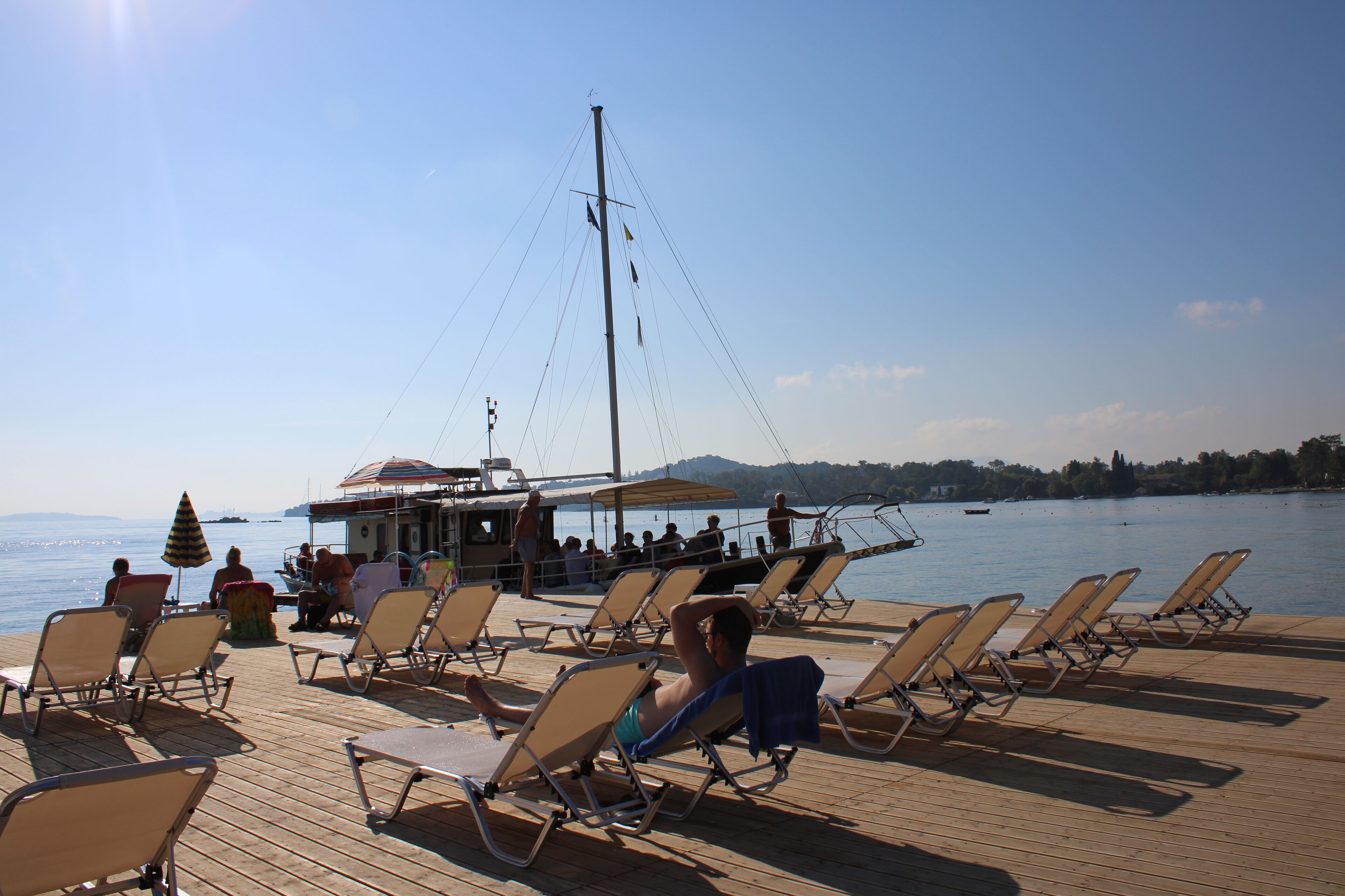 A wooden deck with rows of sun loungers facing a body of water.