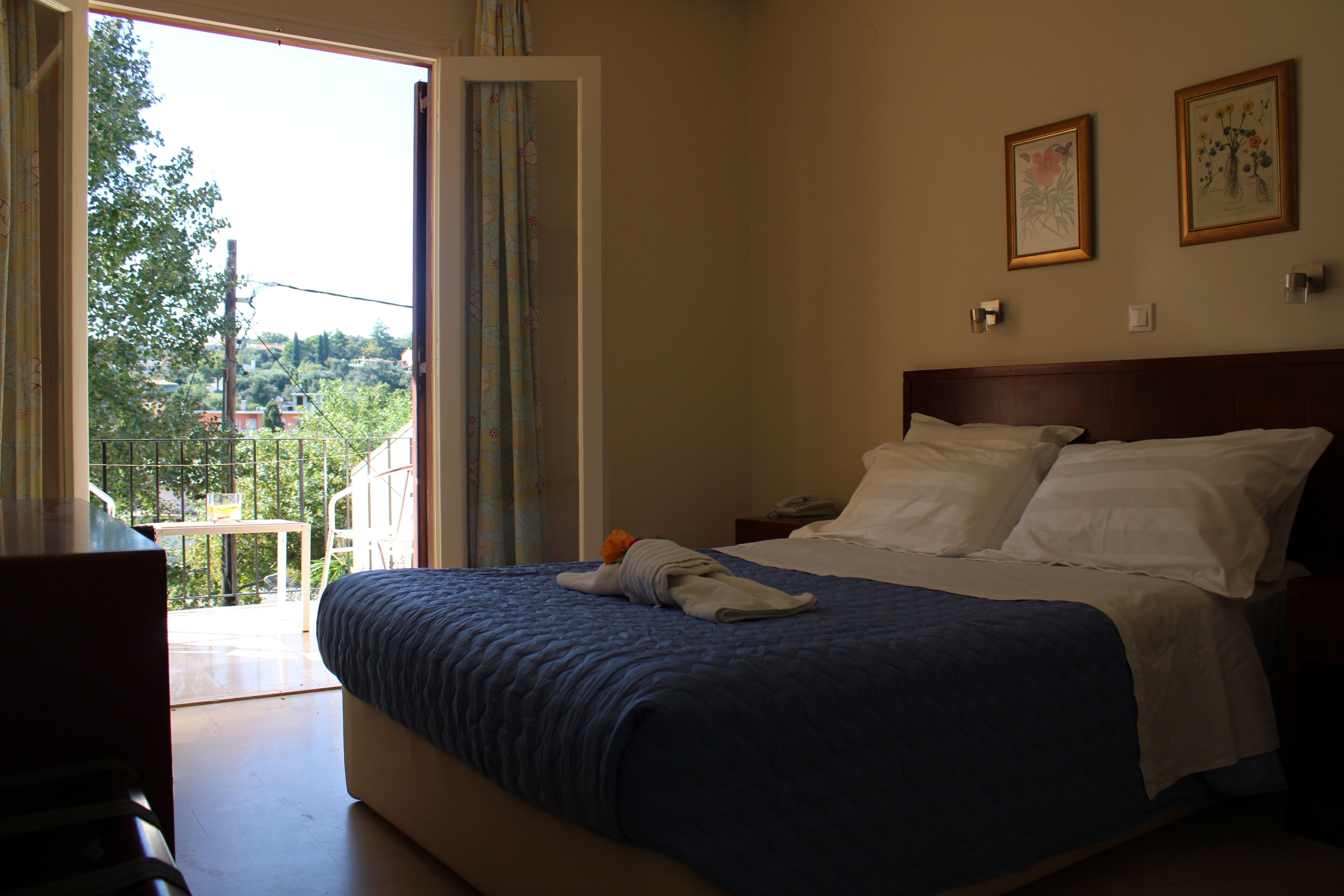 Una habitación de hotel con cama, mesita de noche, escritorio y vistas al exterior.