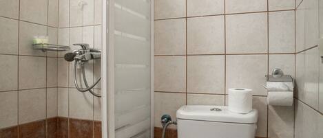 A bathroom with a glass shower enclosure, a toilet, and a towel rack.