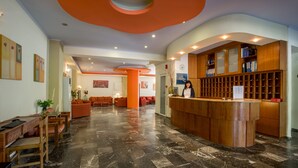 Um hall de entrada com balcão de recepção, área de estar e piso de mármore.