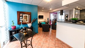 A modern kitchen with a dining area, blue walls, and a tiled floor. - Citotel Furania (Saint-Etienne)