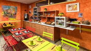 A brightly colored cafe with red and yellow tables, green chairs, and a variety of food items displayed on shelves. - Citotel Furania (Saint-Etienne)