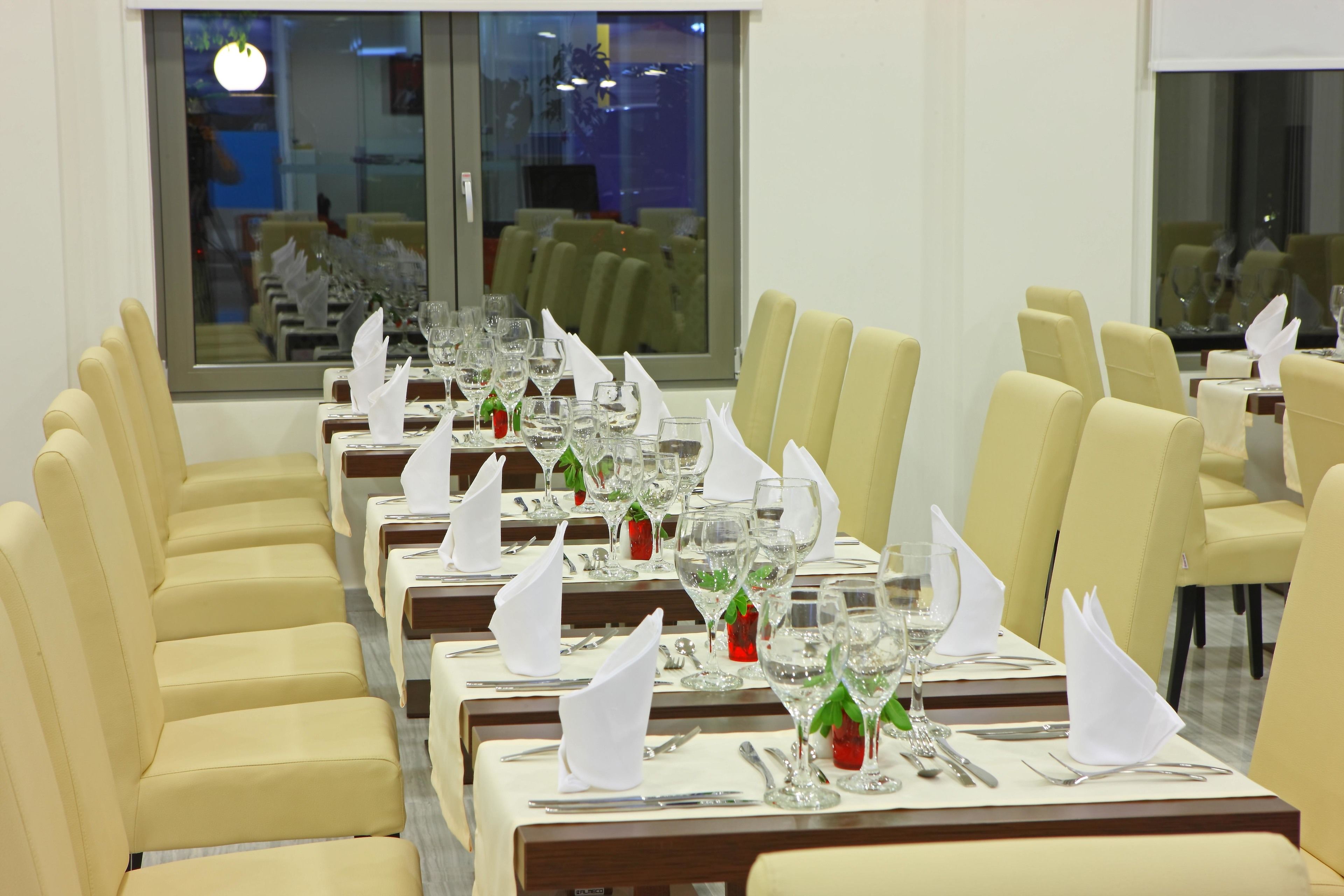 A restaurant with multiple tables set for dining, each with white napkins, cutlery, and glassware.