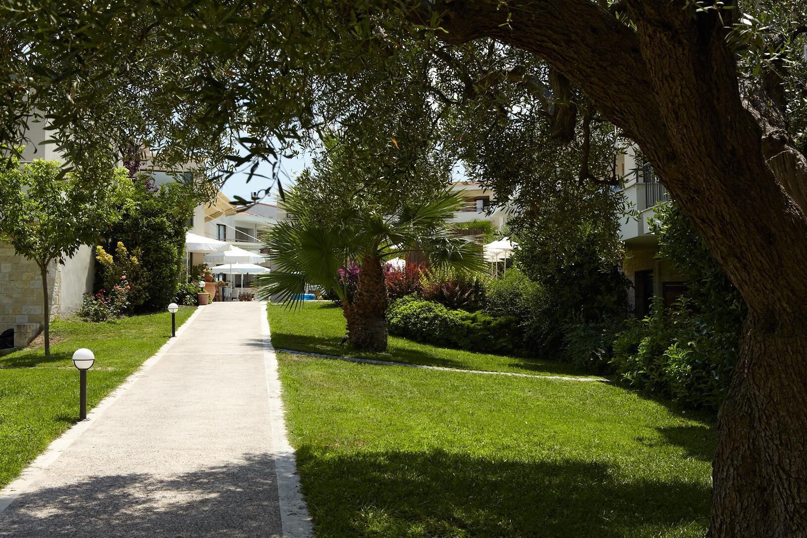 Un sendero conduce a un edificio con terraza al aire libre y un jardín cuidado.