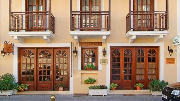 A hotel with three balconies, wooden doors, and potted plants. - Olympic Hotel (Delphi)