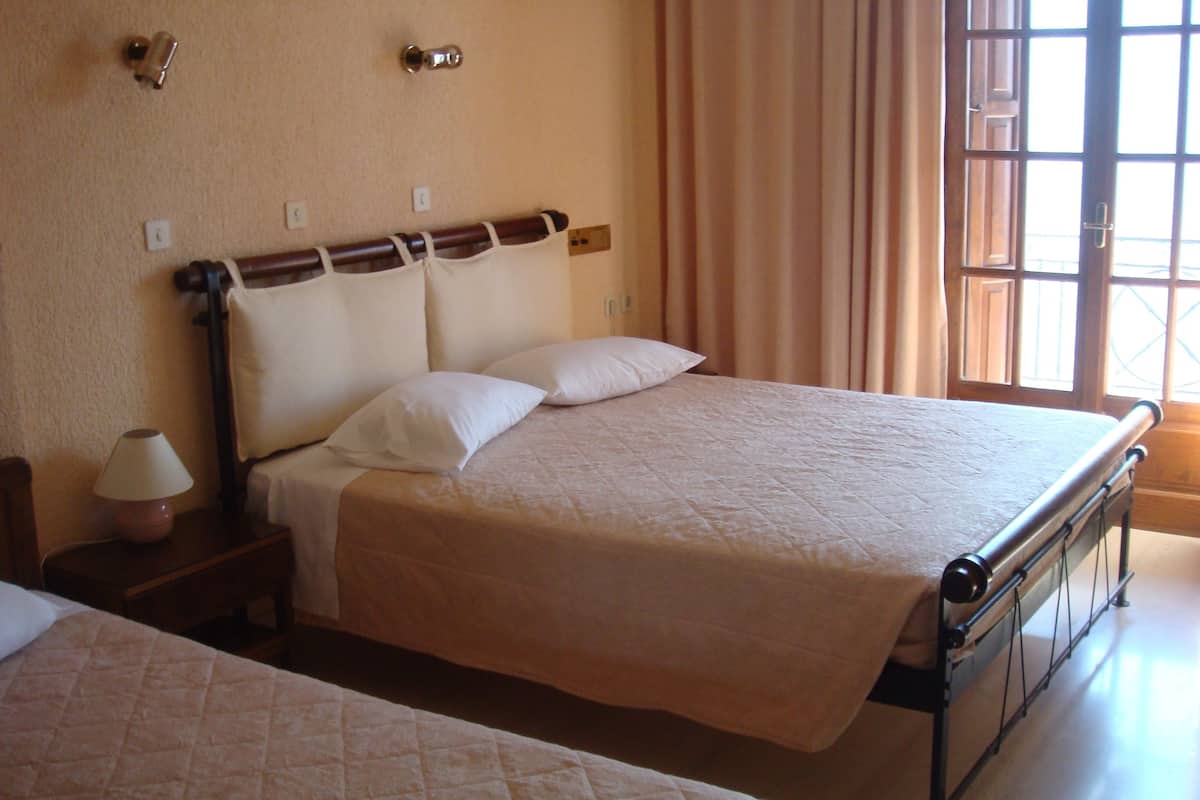 A hotel room with two beds, a nightstand with a lamp, and a window with curtains.