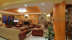 A spacious living room with a fireplace, comfortable seating, and a television. - Olympic Hotel (Delphi)