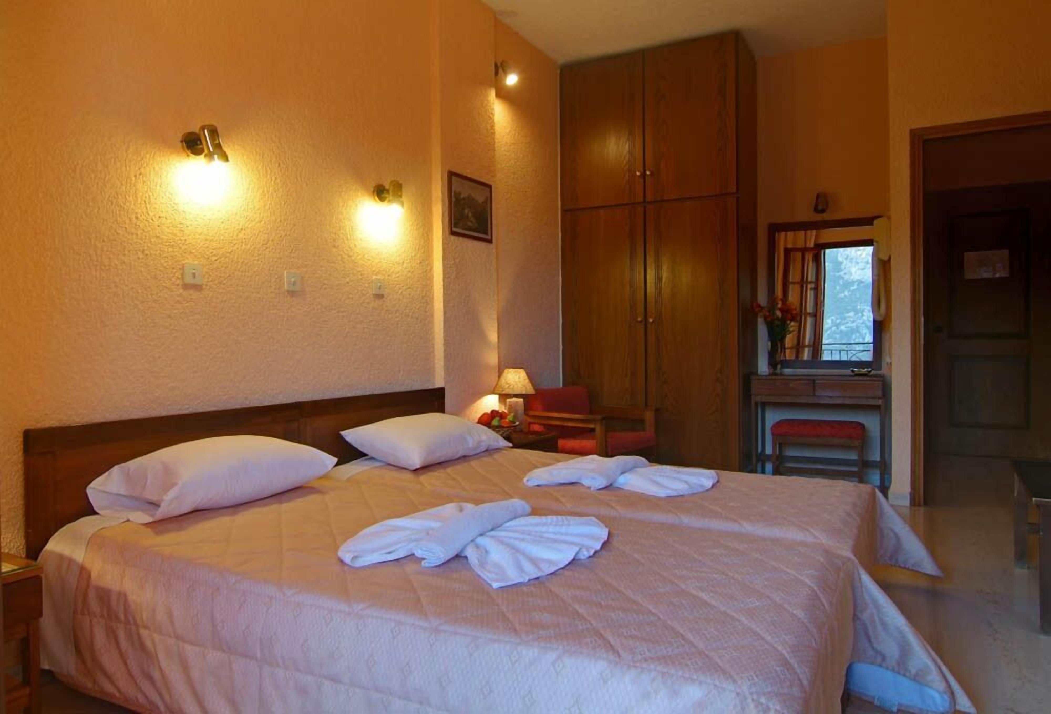 A hotel room with a large bed, a desk, and a wardrobe.
