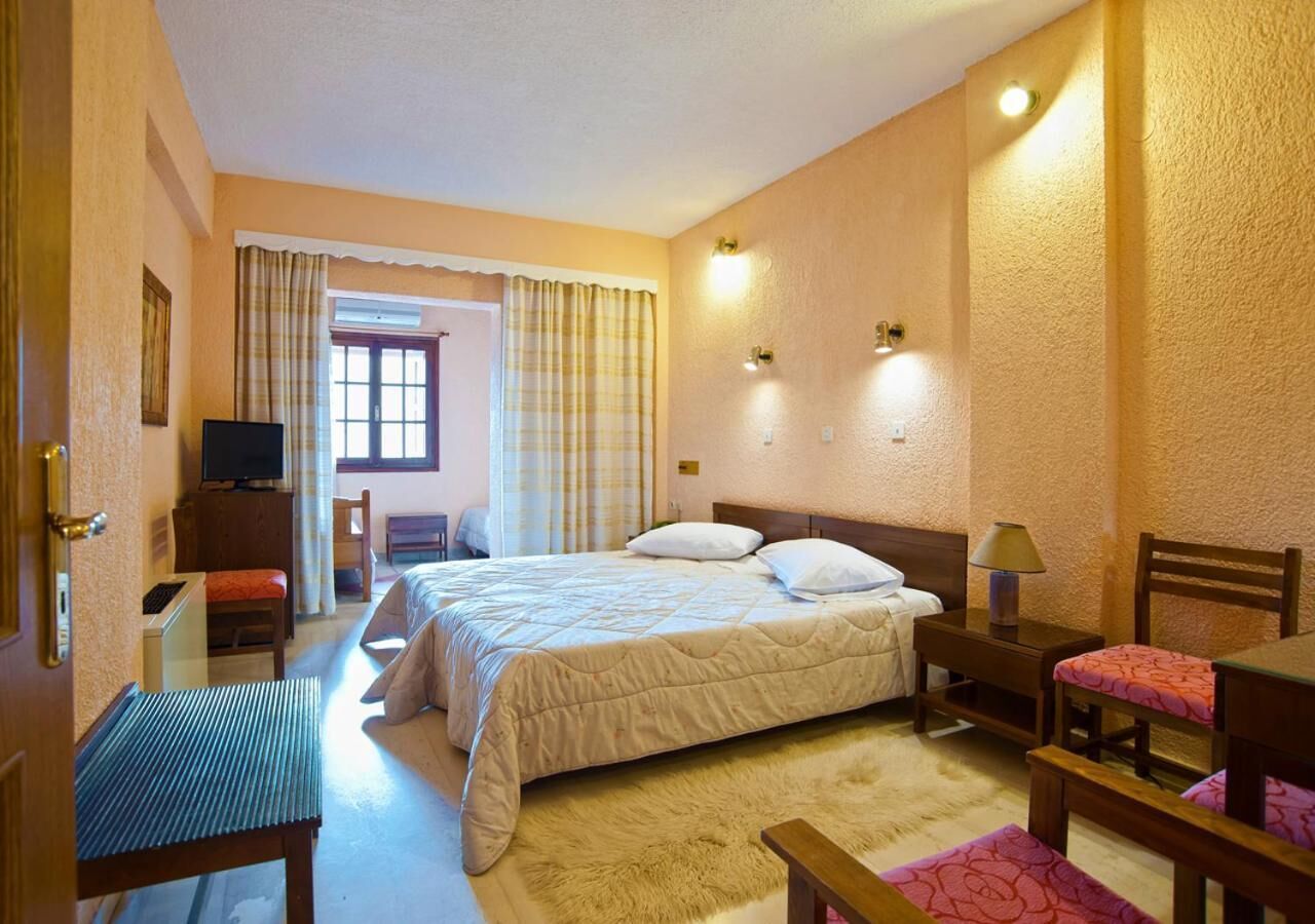 Ein Hotelzimmer mit Bett, Schreibtisch, Stuhl, Fernseher und einem Fenster mit Vorhängen.