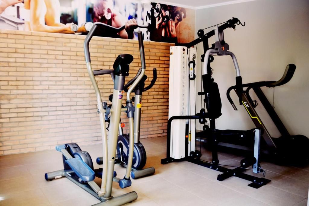 Ein Fitnessraum mit verschiedenen Trainingsgeräten, darunter ein Fahrradergometer, ein Rudergerät und eine Beinpresse.