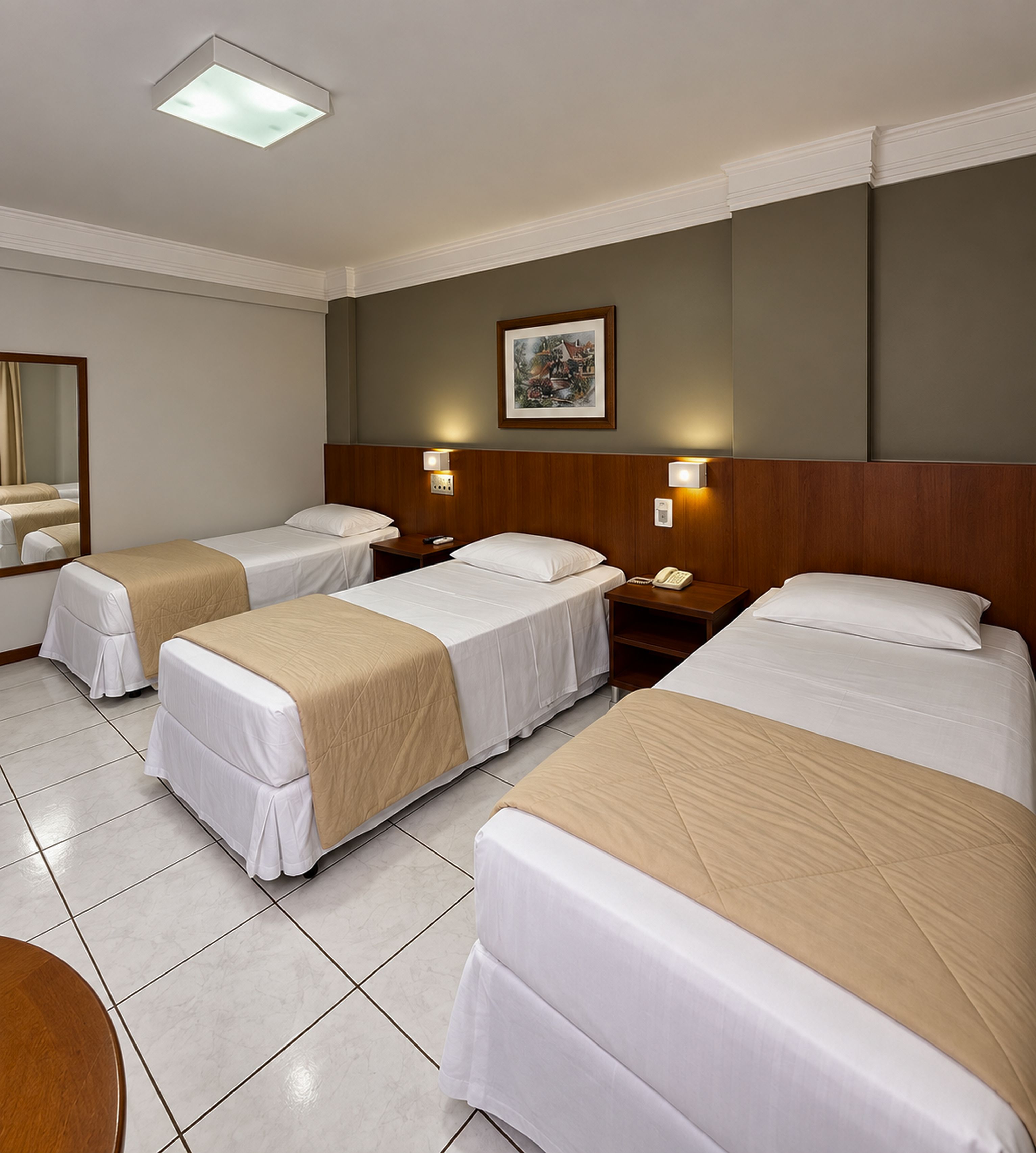 A hotel room with four single beds, a large mirror, and a framed picture on the wall.