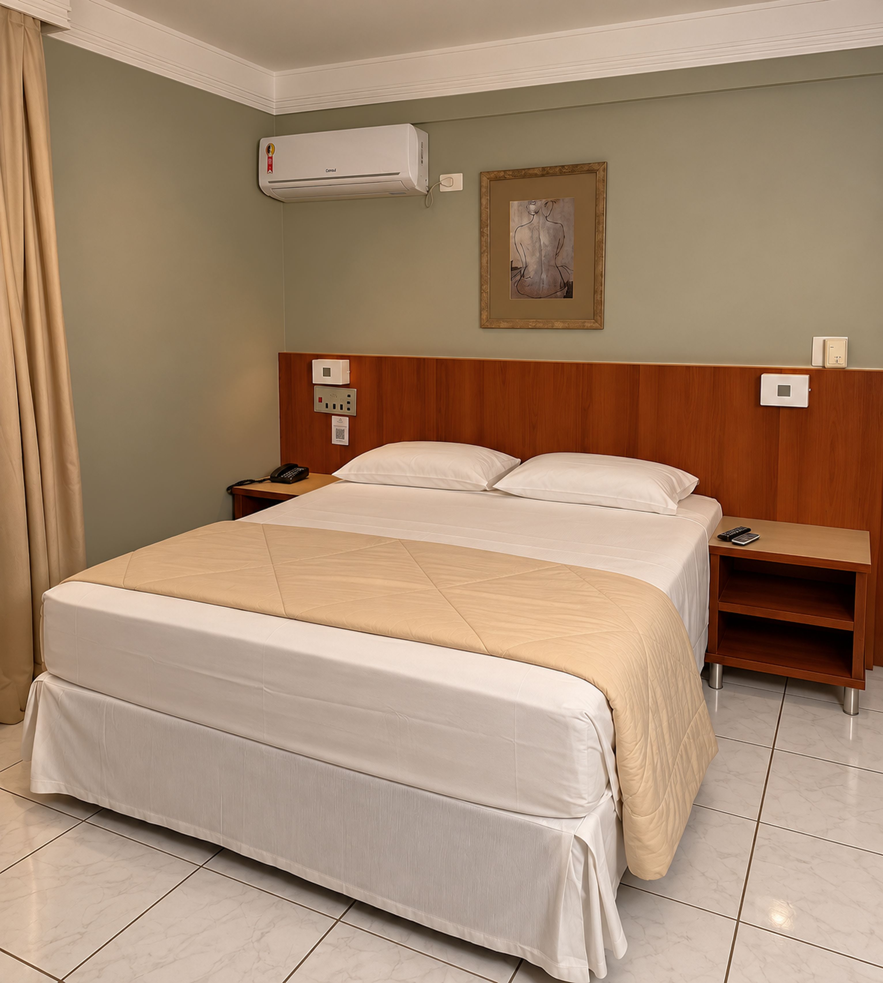 A hotel room with a bed, a nightstand, an air conditioning unit, a painting, and a control panel.