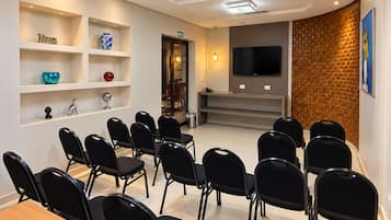 Kokoushuone, jossa on pitkä pöytä ja tuolit, seinälle asennettu televisio ja yksi seinä on koristeltu tiilillä.