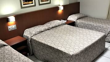A hotel room with two beds, a nightstand, a wall-mounted air conditioner, and two framed pictures on the wall.