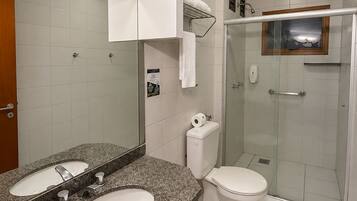 Ein modernes Badezimmer mit einer Naturstein-Arbeitsplatte, zwei Waschbecken, einer Toilette und einer Duschkabine.