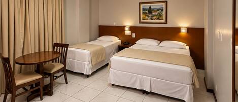 A hotel room with two beds, a dining table, and chairs.