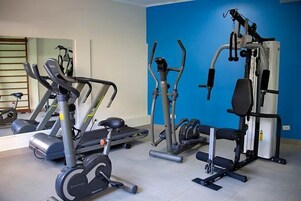 Un gimnasio con equipos de ejercicio variados, incluyendo cintas de correr, elípticas y máquinas de pesas.