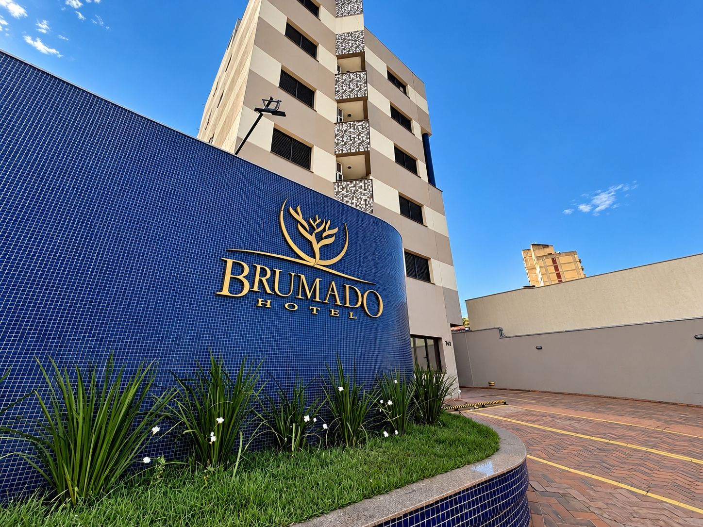 Exterior do Hotel Brumado, com fachada em azulejos azuis e céu limpo.