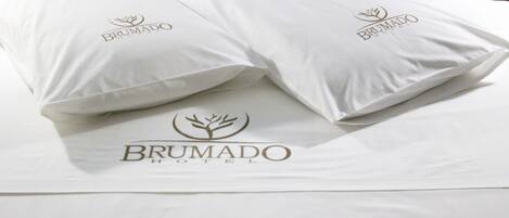 Dos almohadas con el logotipo del Hotel Brumado sobre la cama.