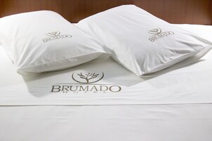 Dos almohadas con el logotipo del Hotel Brumado sobre la cama.