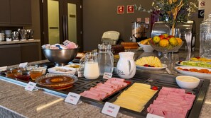 A buffet with various food options including meats, cheeses, fruits, and condiments. - Brumado Hotel (Campo Grande)