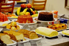 A buffet with various food items including cakes, fruits, and bread. - Brumado Hotel (Campo Grande)