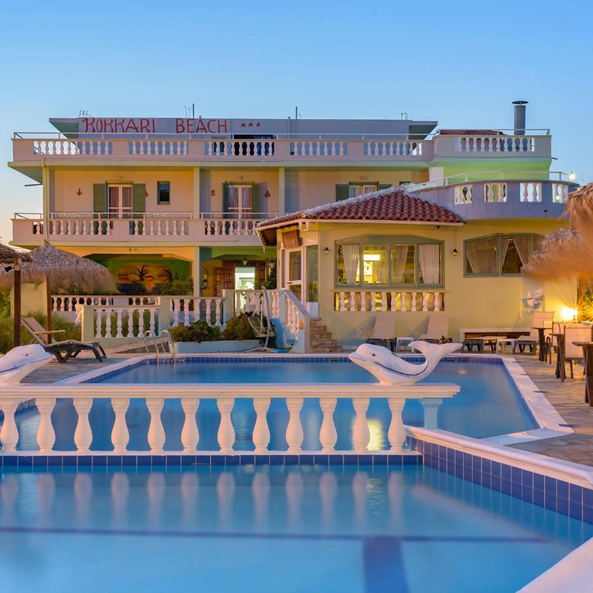 Un hôtel doté d’une piscine, de plusieurs balcons et d’une enseigne indiquant « KOKKARI BEACH ».
