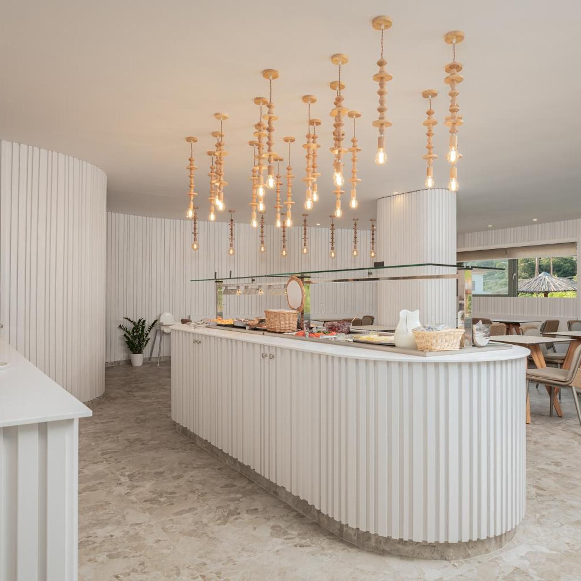 A modern kitchen with a central island, pendant lighting, and a view of the outdoors.