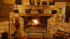 A stone fireplace with a fire, surrounded by various pots and kettles. - Hotel Pousada do Arcanjo (Ouro Preto)