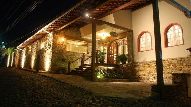A stone building with a wooden staircase leading to a porch. - Hotel Pousada do Arcanjo (Ouro Preto)