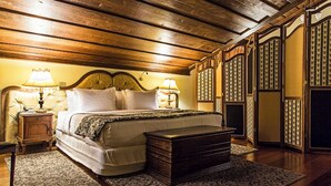 A traditional bedroom with a wooden ceiling, a large bed with two bedside tables, and a chest of drawers. - Hotel Pousada do Arcanjo (Ouro Preto)