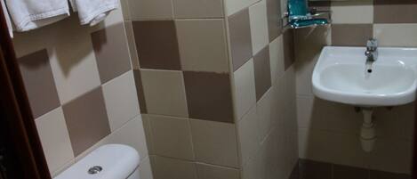 A bathroom with a toilet, sink, and tiled walls.