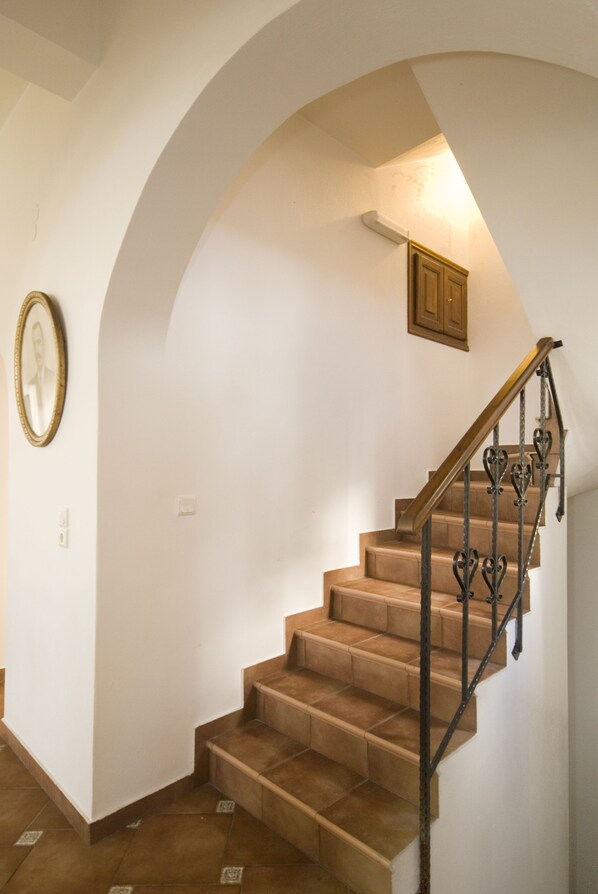 A staircase with a wooden handrail and a wall-mounted light fixture.