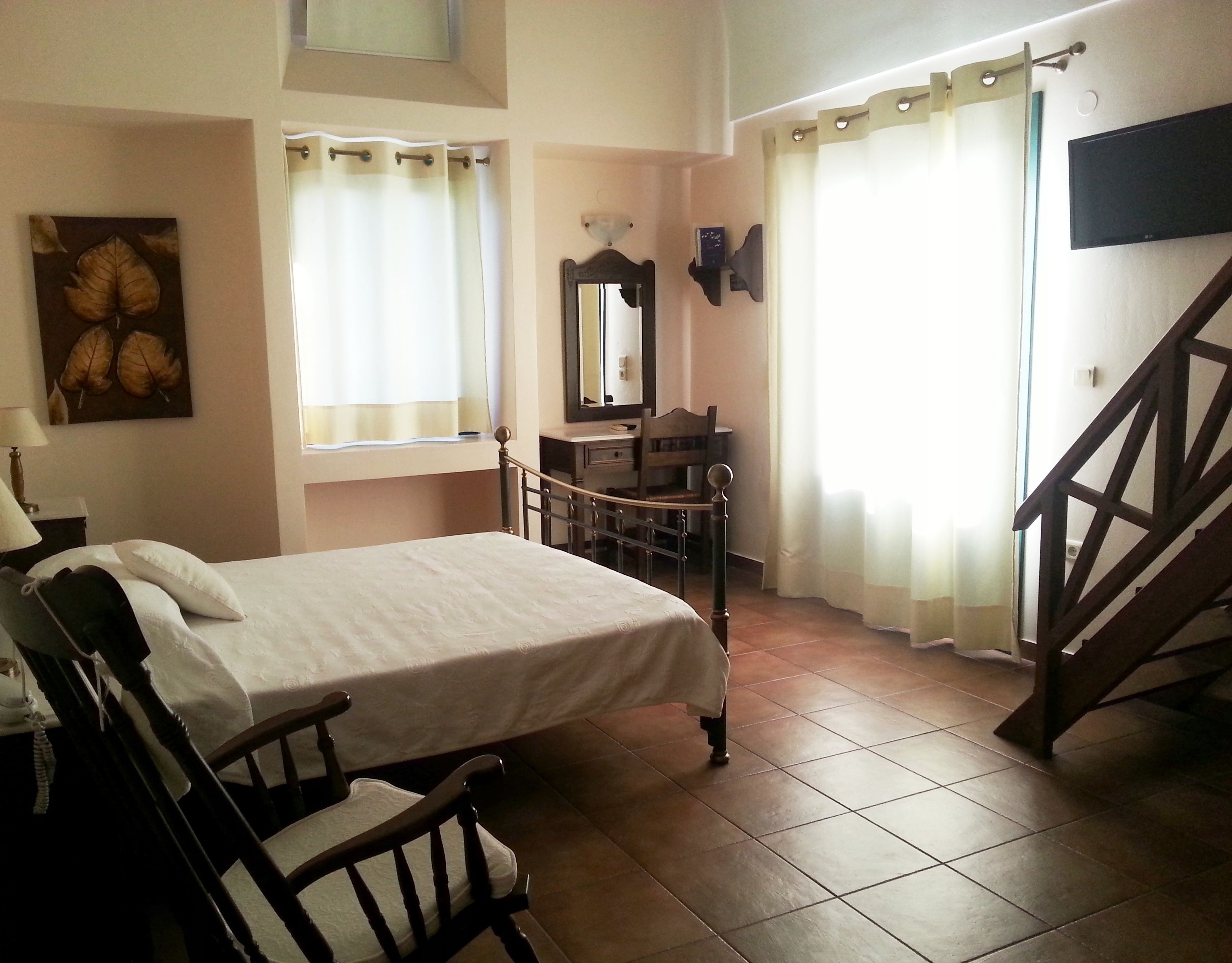 A bedroom with a bed, a chair, a dresser, a mirror, and a staircase.