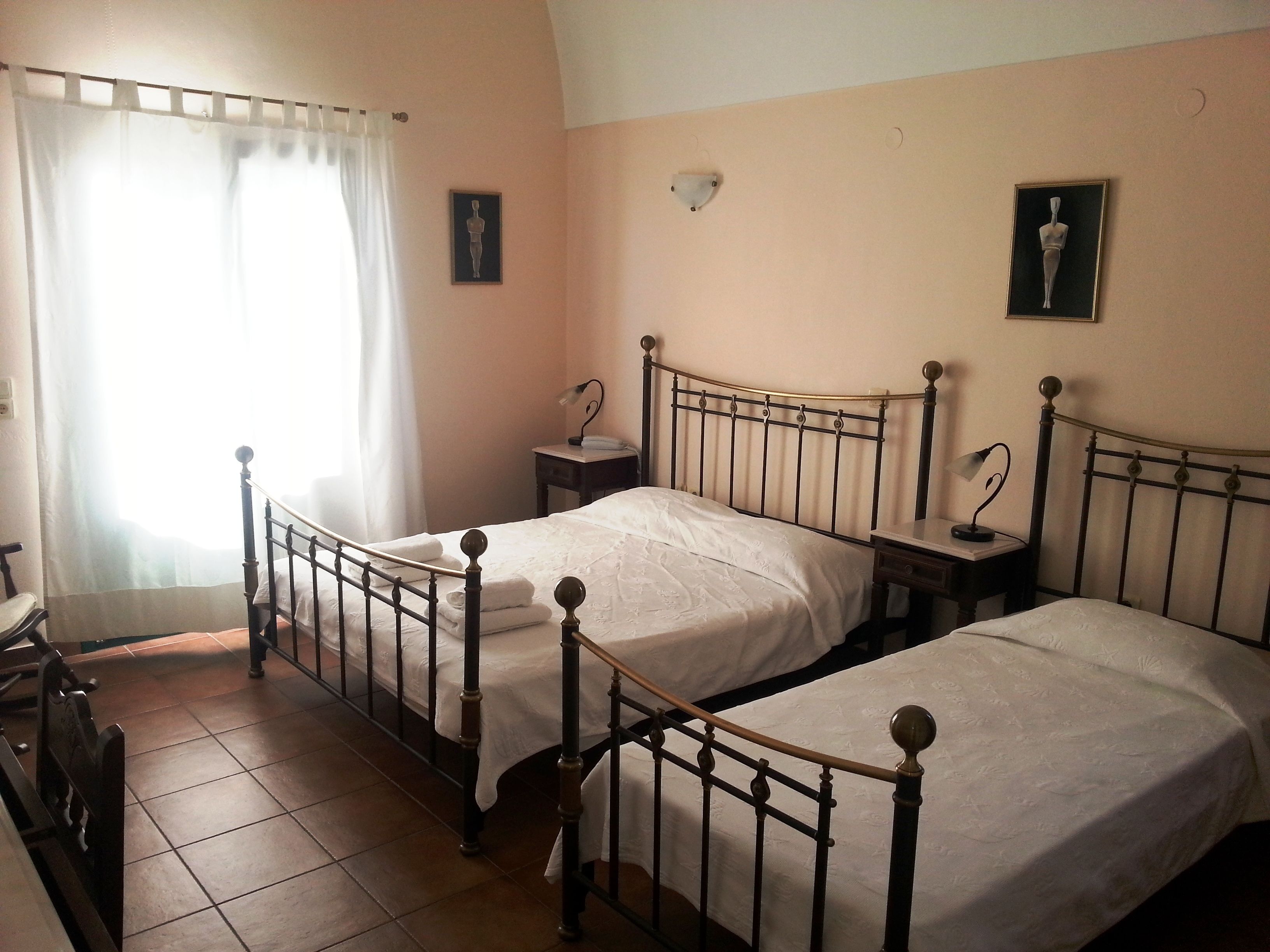 Une chambre avec deux lits, une table de chevet, une chaise et une fenêtre avec des rideaux.