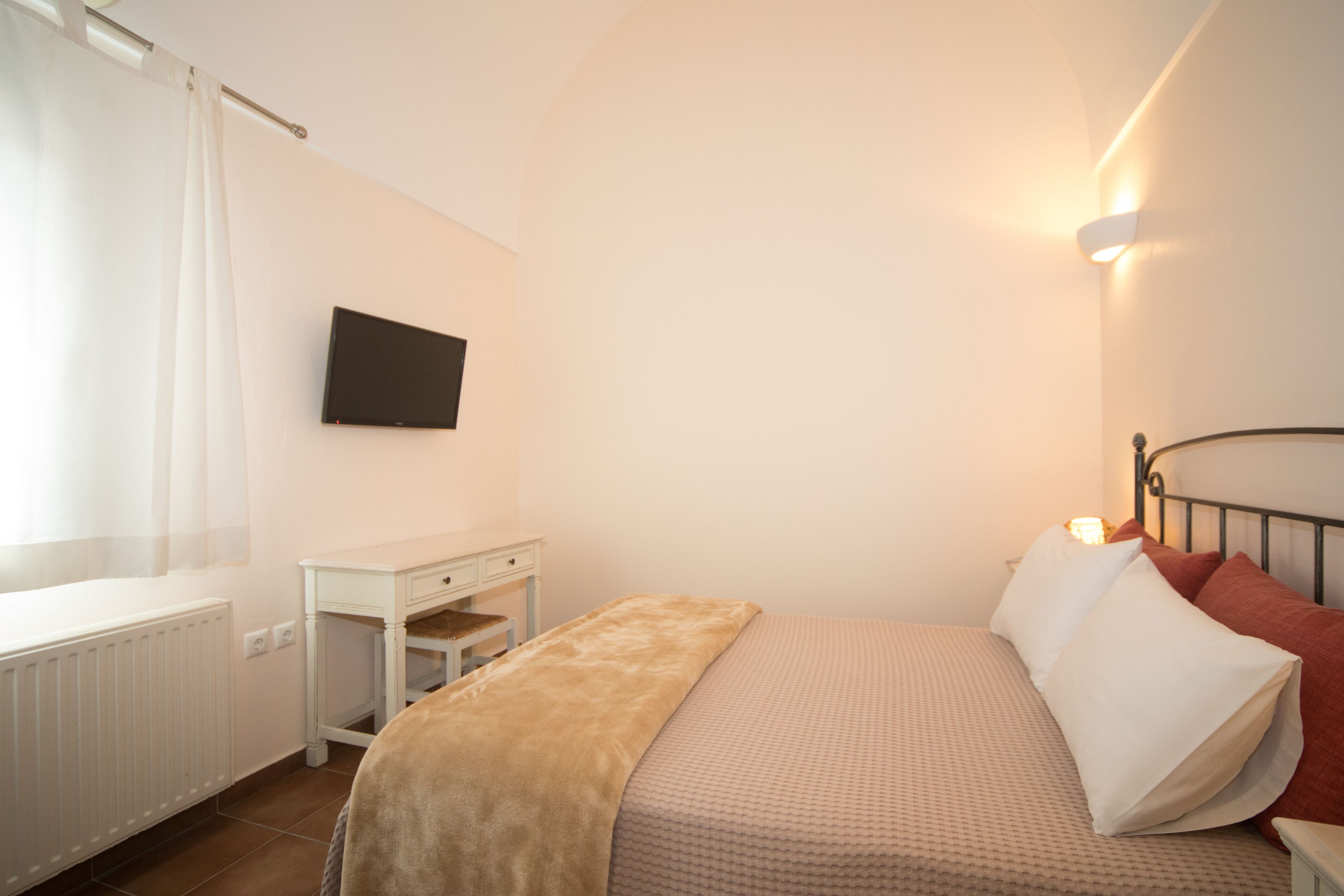 A bedroom with a bed, bedside table, and a mounted TV.